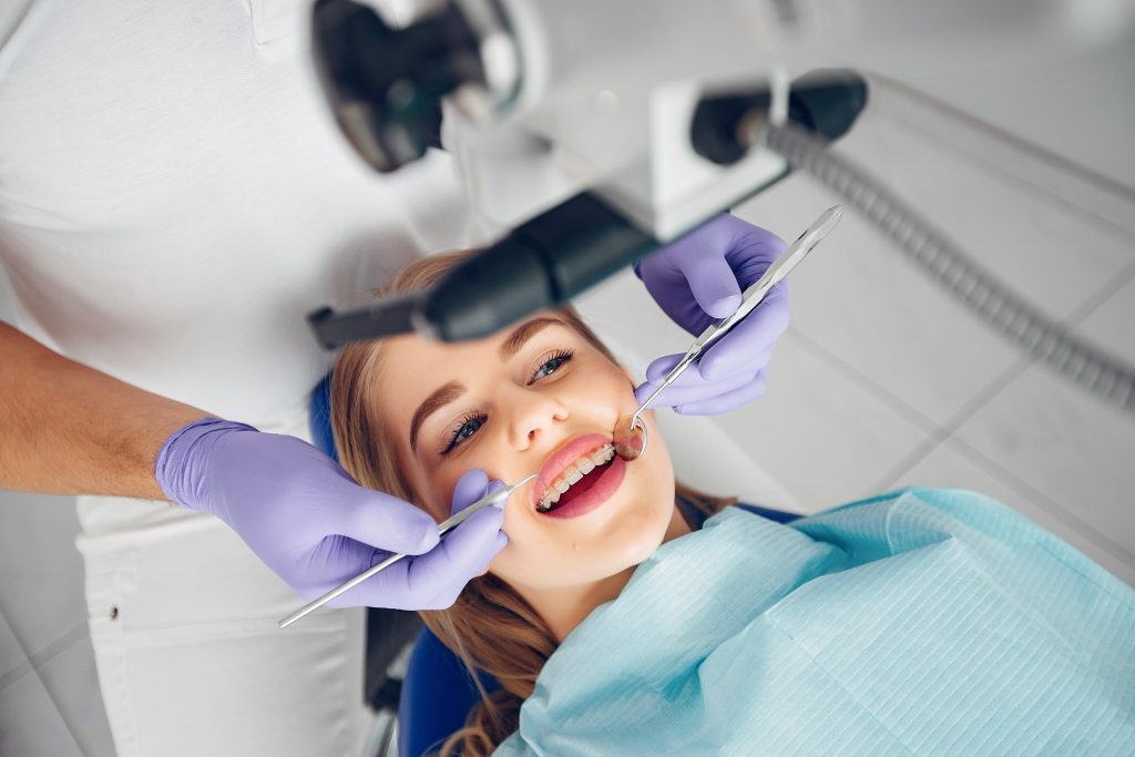 Young woman with braces receiving a dental check-up, illustrating orthodontic care as part of a comprehensive smile makeover treatment.