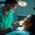 Dentist performing a root canal treatment on a smiling patient under a dental light in a modern clinic.