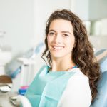 Smiling woman sitting in a dental chair after treatment.