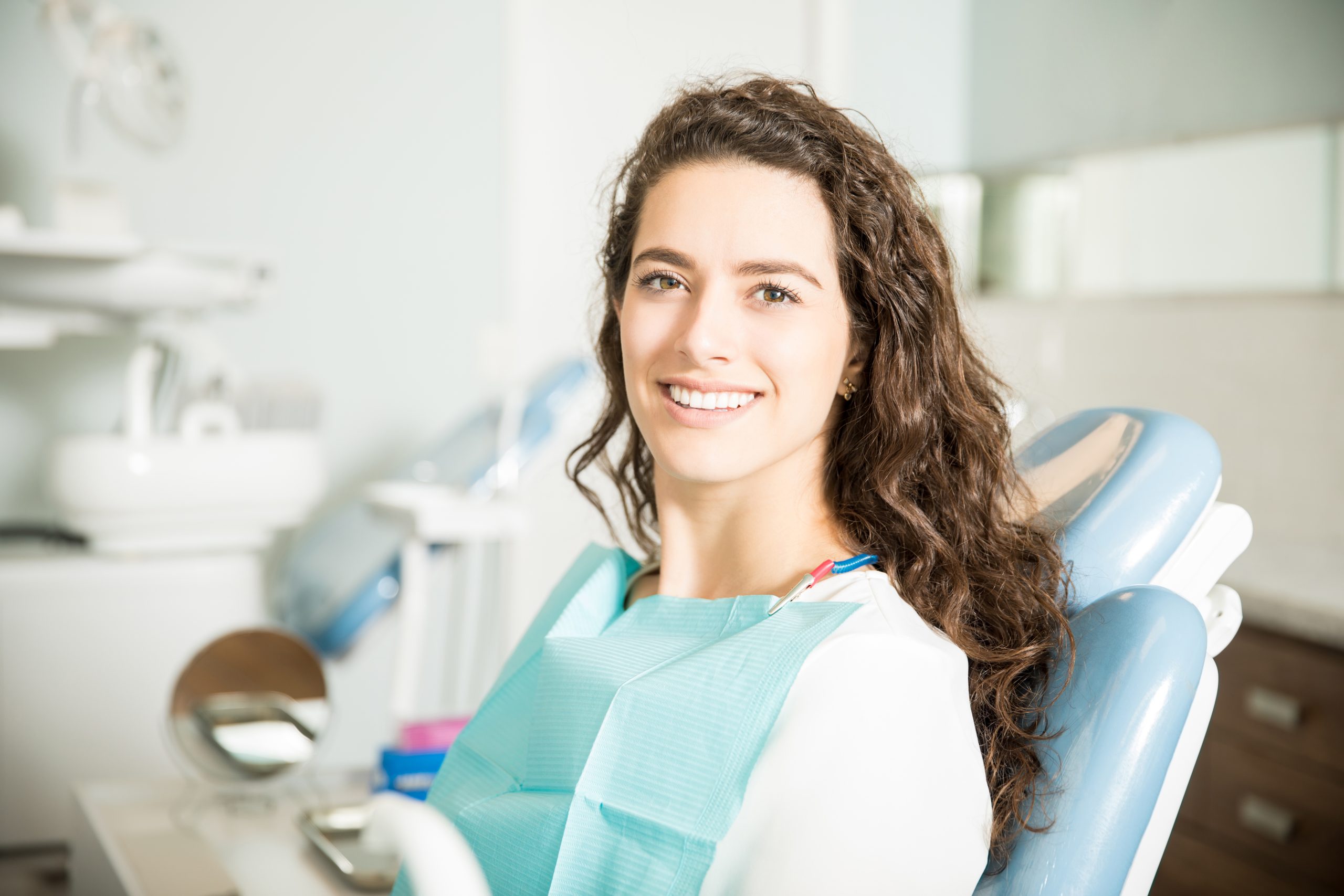 Smiling woman sitting in a dental chair after treatment.